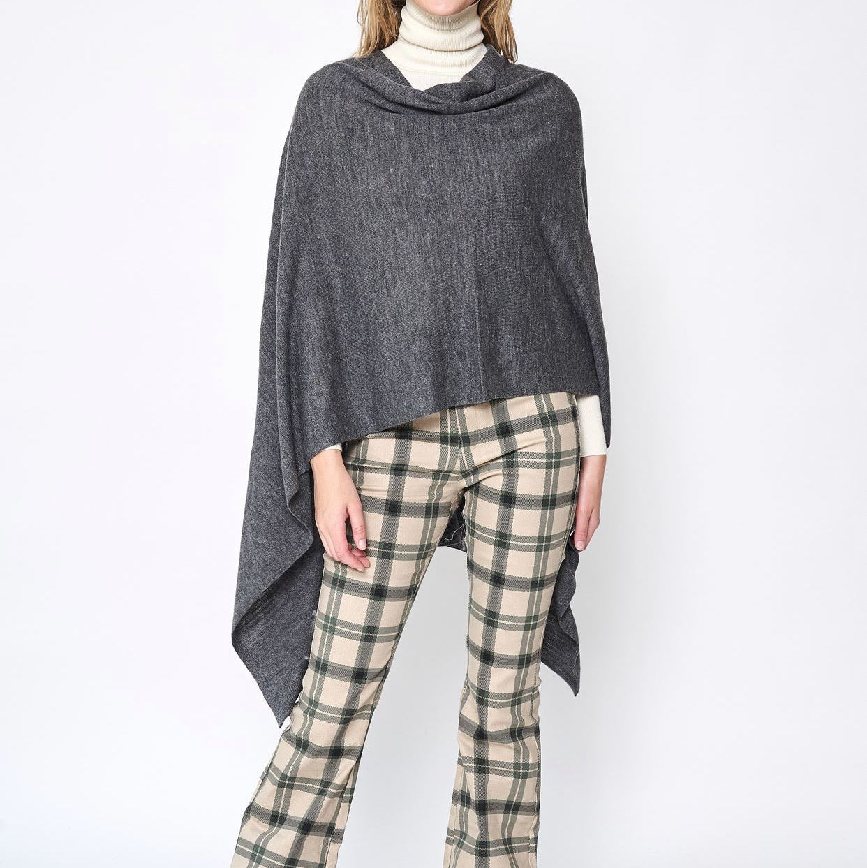 Someone wearing the Take With Me Travel Poncho by Ellison + Young with plaid pants against a plain white background.