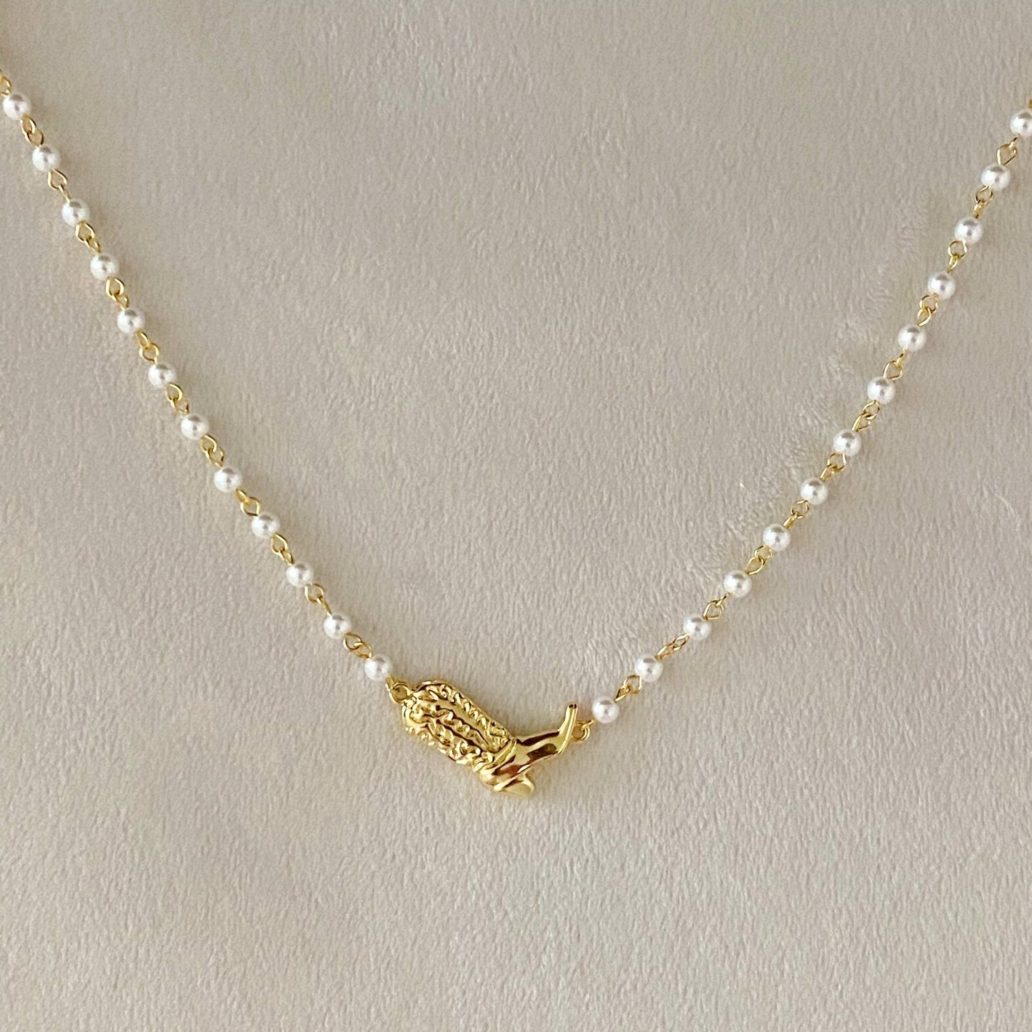 Ellison + Youngs Cowgirl Boot Pearl Chain Necklace is displayed on a marble surface.