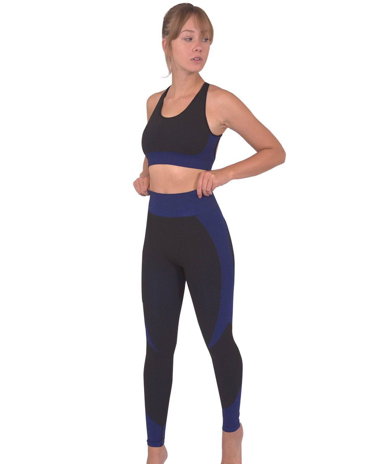 Someone wearing Savoy Actives Trois Seamless Legging in Black with Navy stands on a brown couch in a modern room with plants.
