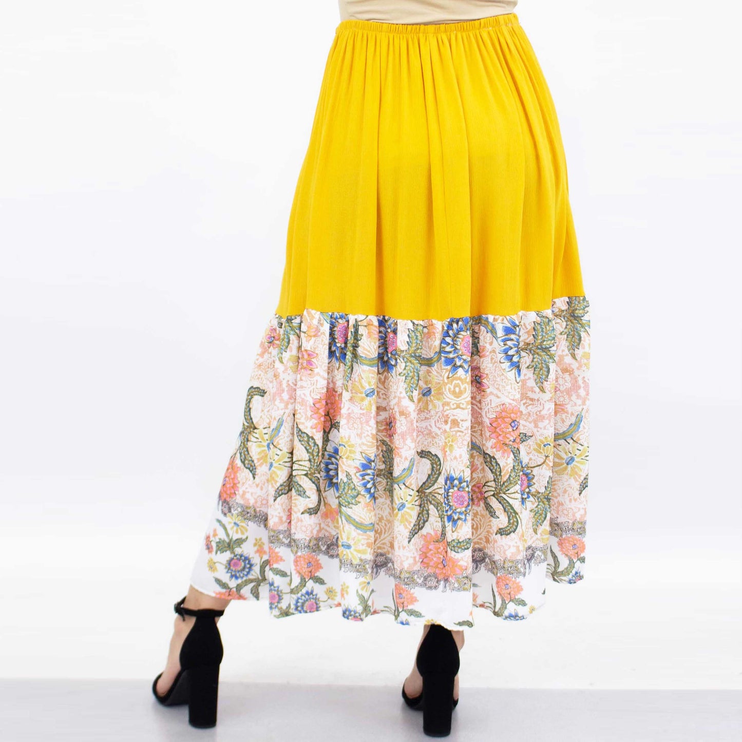 A person wearing a Stylespect Floral Color Block Skirt - Yellow paired with black high heels.
