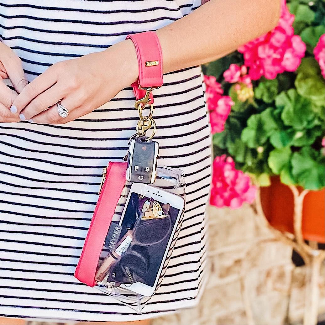 The KEYPER Bright Pink Vegan Leather 2-Piece WRISTLET SET includes a small pink pouch with a zipper, gold clasp, an attached pink strap, and a set of keys.