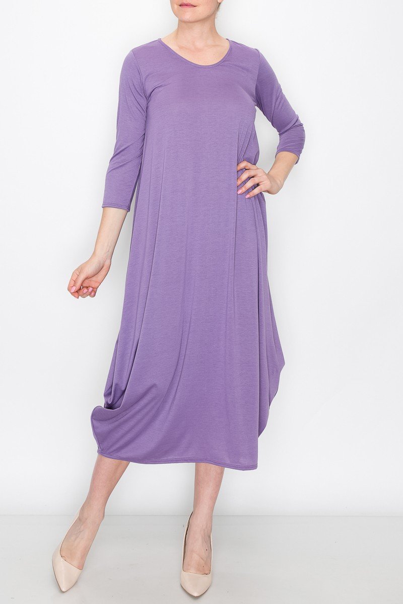 A person models the Stylespect Solid Balloon Dress in purple with its long sleeves and asymmetrical cut, paired with beige heels, all set against a plain white background.