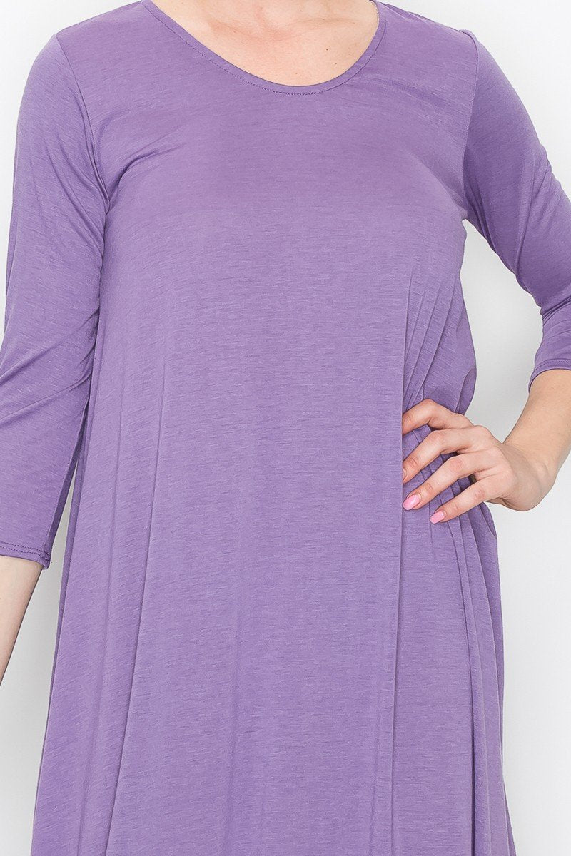 A person models the Stylespect Solid Balloon Dress in purple with its long sleeves and asymmetrical cut, paired with beige heels, all set against a plain white background.
