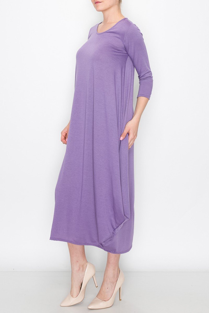 A person models the Stylespect Solid Balloon Dress in purple with its long sleeves and asymmetrical cut, paired with beige heels, all set against a plain white background.