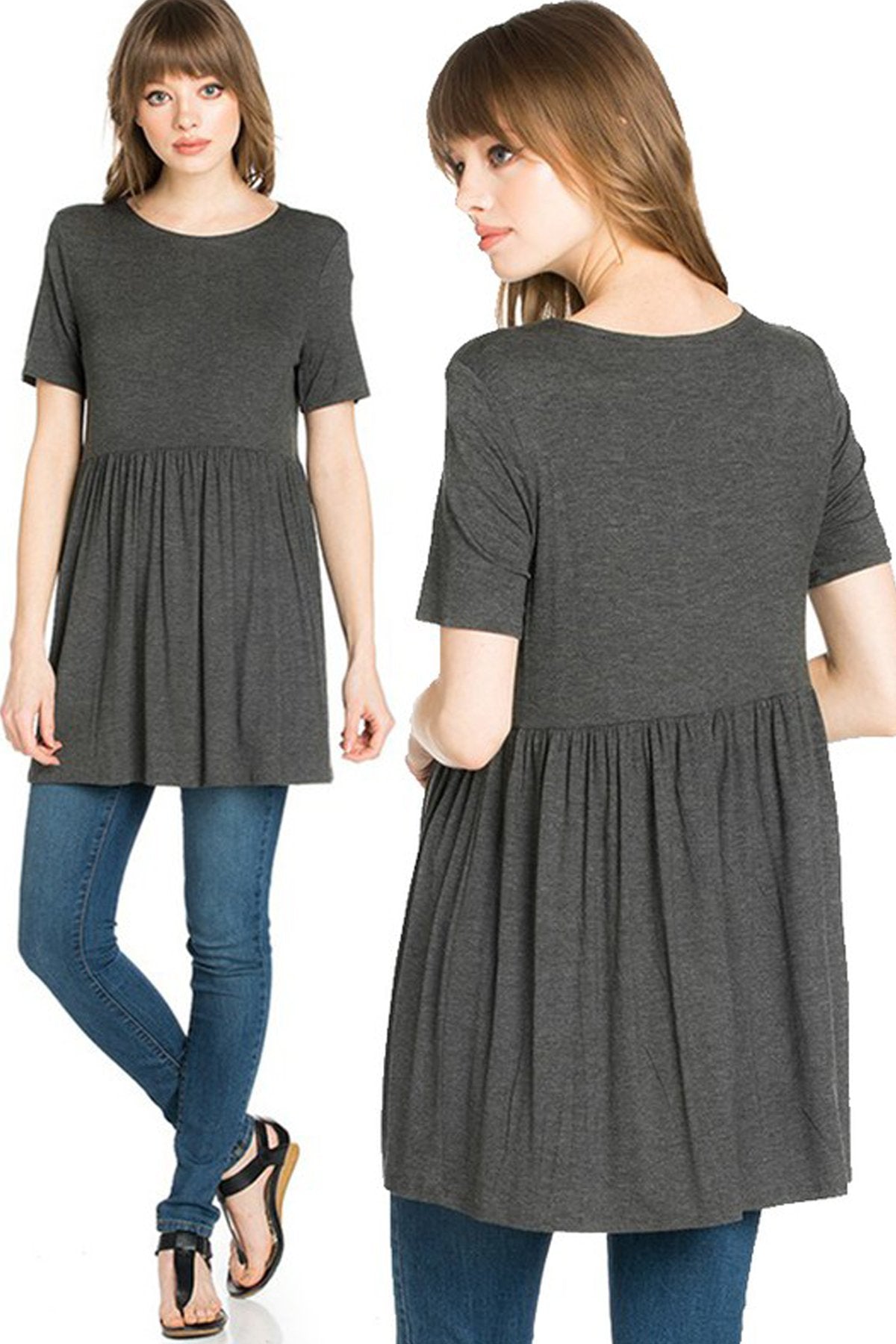 A woman stands outdoors wearing a beige Riah Fashion Short Sleeve Empire Waist Tunic paired with a long necklace.
