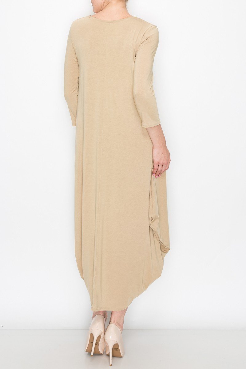 A person poses against a white background wearing the Stylespect Solid Balloon Dress in beige, featuring long sleeves and paired with beige heels, with one hand on their hip.