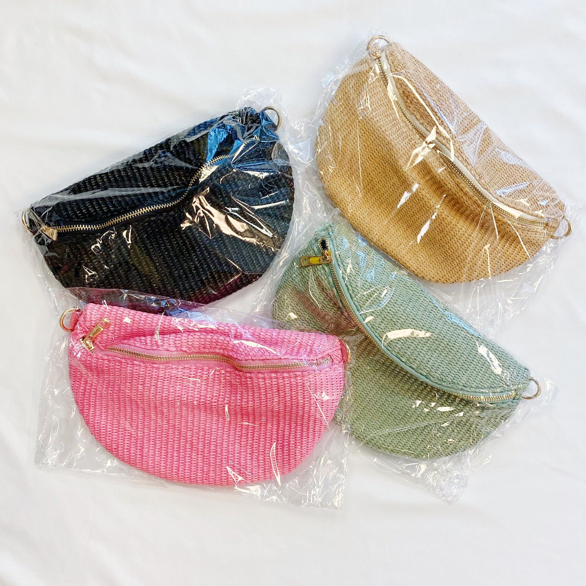 Four Bahama Breeze Fit All Sling Bags by Ellison + Young in pink, black, beige, and green with unique patterned straps are displayed on a white surface.