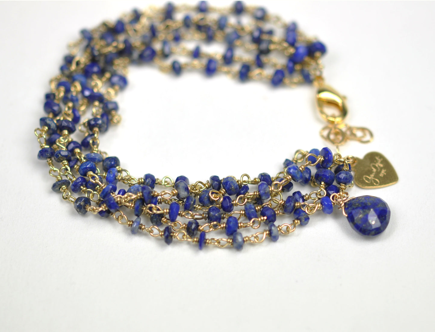 Gena Myints Lapis Lazuli Bracelet features gold and blue multi-strands, a lobster clasp, and a heart-shaped charm.
