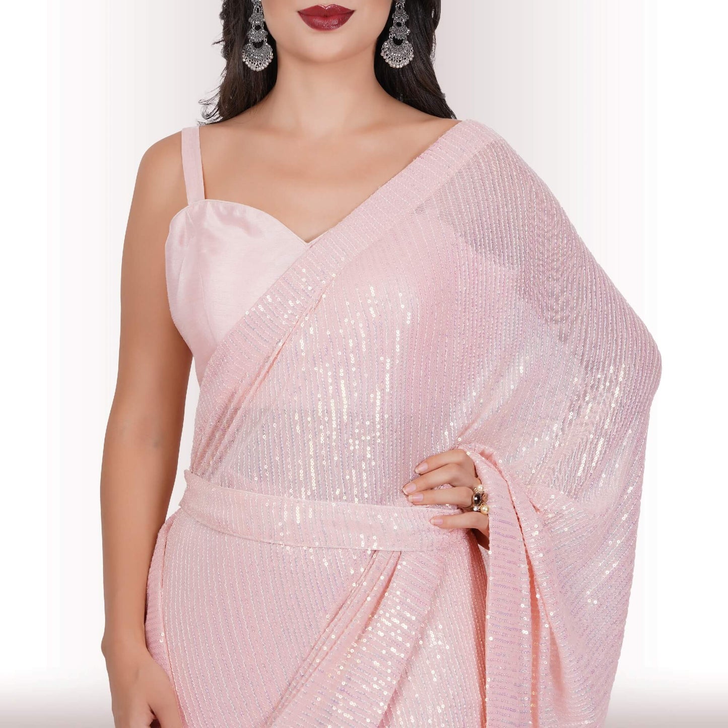 A person wearing Chiros Ready Made Sequin Saree in Blush poses with one hand on their hip against a light background.