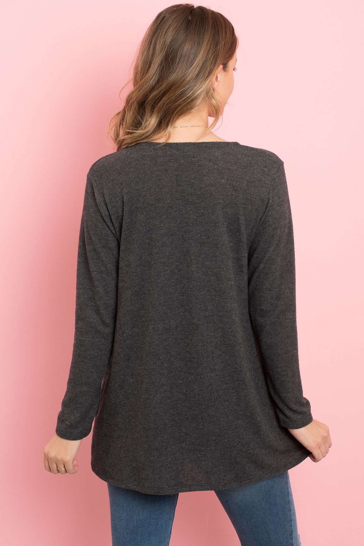 A woman in a teal Solid Long Sleeved Open Front Pocket Cardigan by Riah Fashion over a beige top stands against a pink background, smiling with hands in pockets.