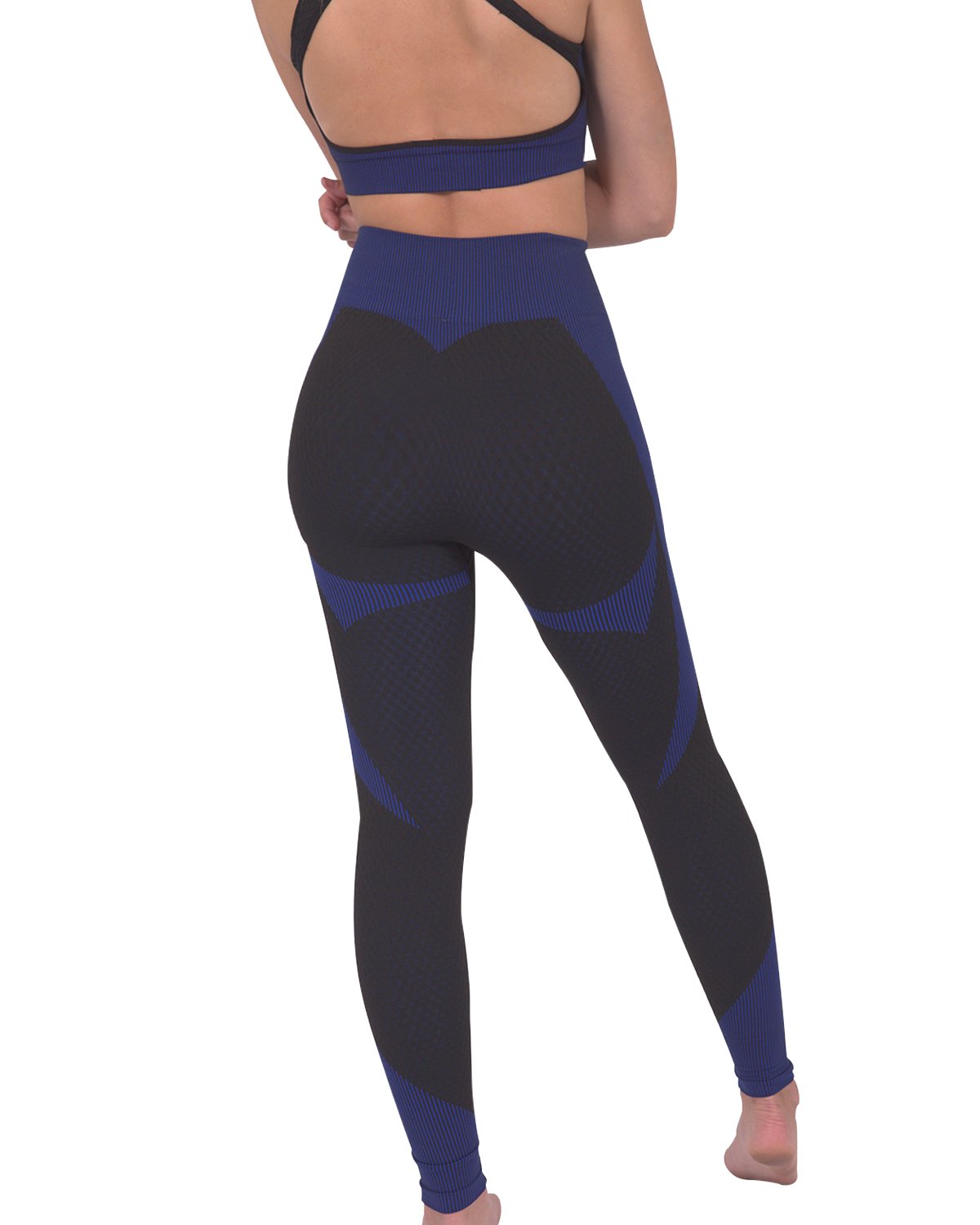 Someone wearing Savoy Actives Trois Seamless Legging in Black with Navy stands on a brown couch in a modern room with plants.