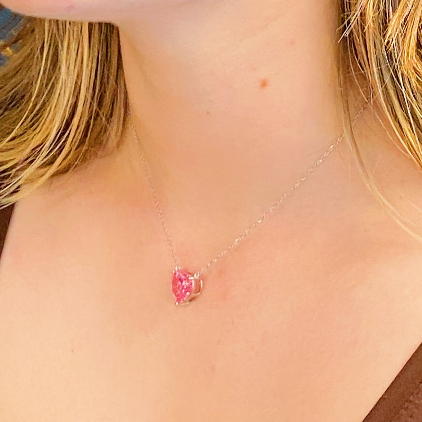 Two Absolute Beauty sterling silver heart necklaces by Ellison + Young; one with a pink gem, the other with a clear gem, against a white background.