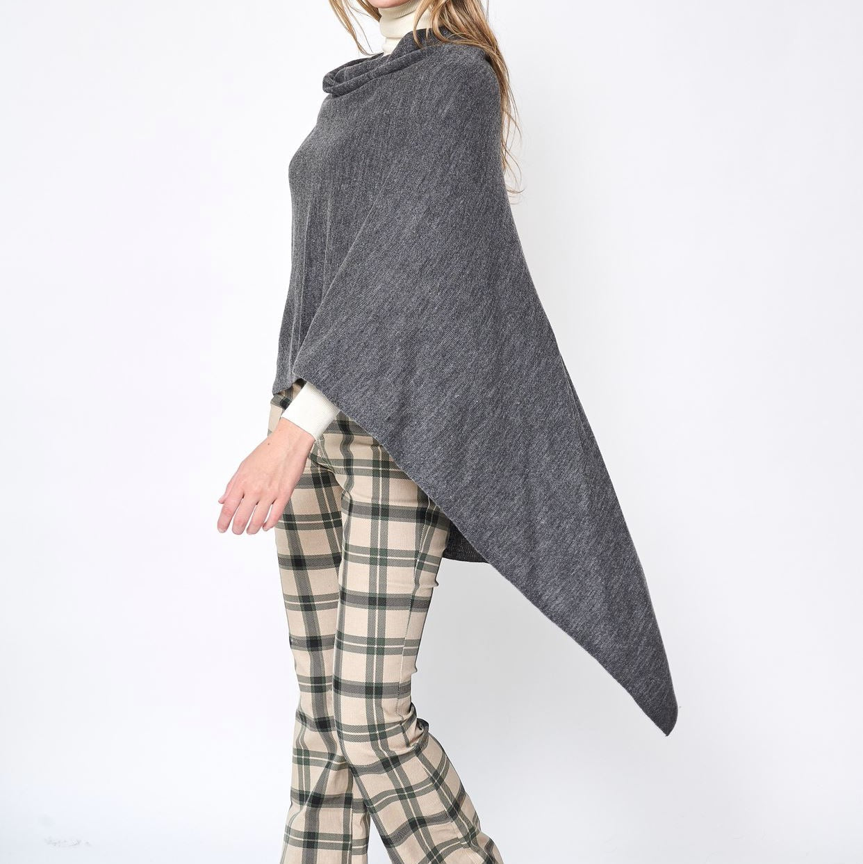 Someone wearing the Take With Me Travel Poncho by Ellison + Young with plaid pants against a plain white background.
