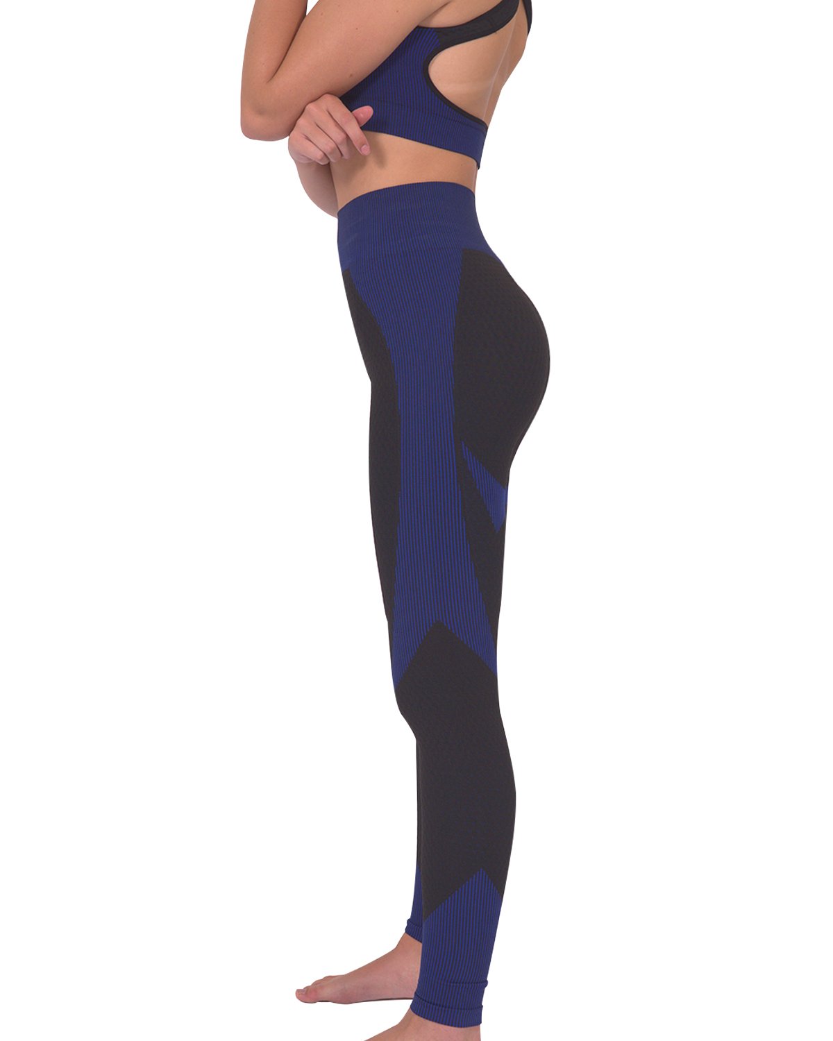 Someone wearing Savoy Actives Trois Seamless Legging in Black with Navy stands on a brown couch in a modern room with plants.