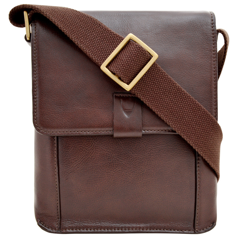 The Aiden Genuine Leather Mini Crossbody by Hidesign is a brown leather shoulder bag featuring a flap cover and an adjustable fabric strap with a brass buckle.