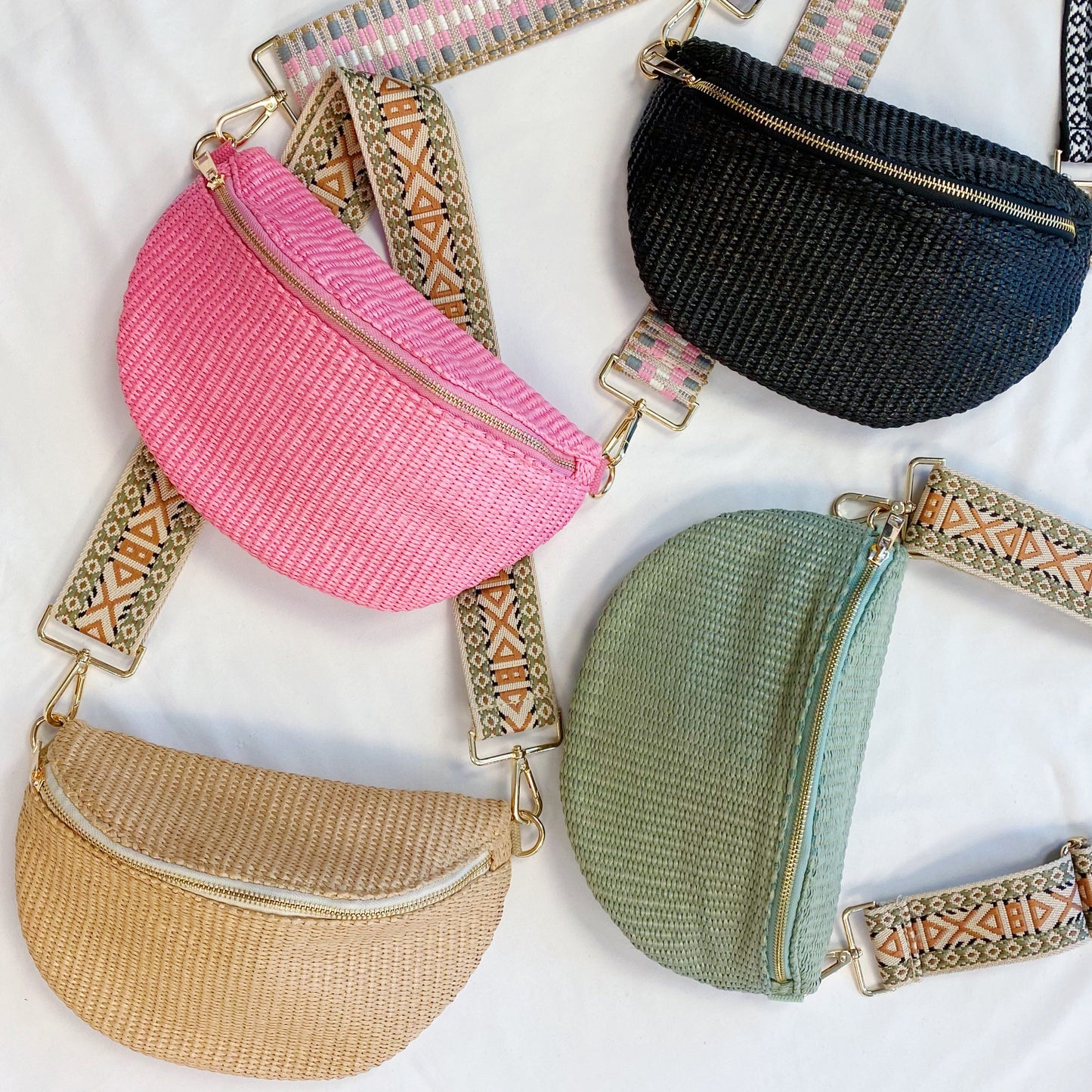 Four Bahama Breeze Fit All Sling Bags by Ellison + Young in pink, black, beige, and green with unique patterned straps are displayed on a white surface.