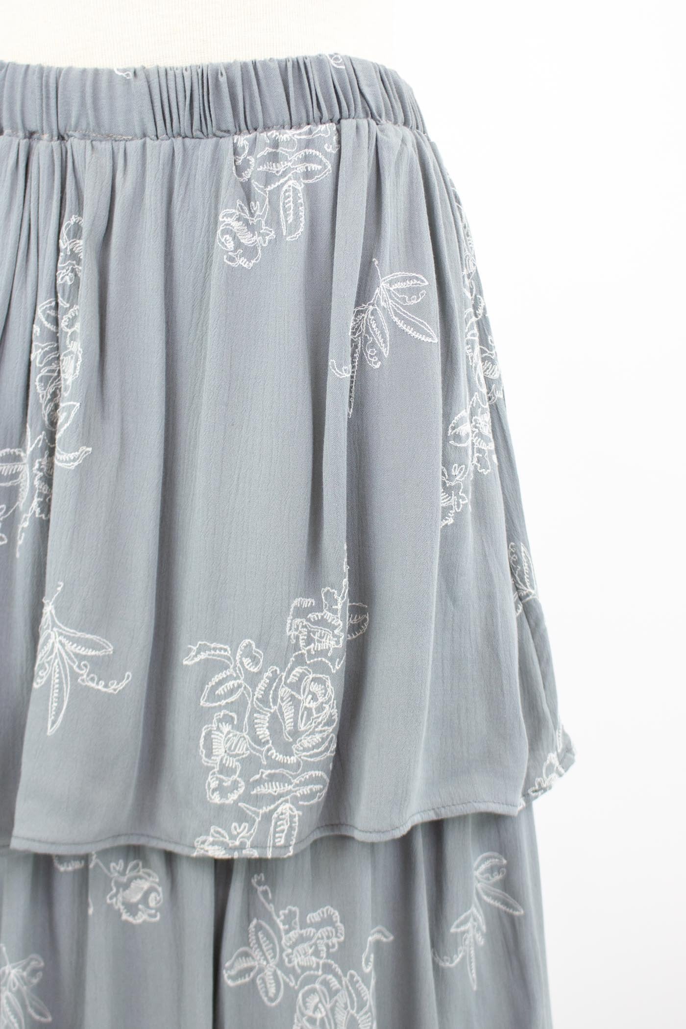 The mannequin displays the Stylespect Layered Ruffle Maxi Skirt in light gray, featuring white floral embroidery.