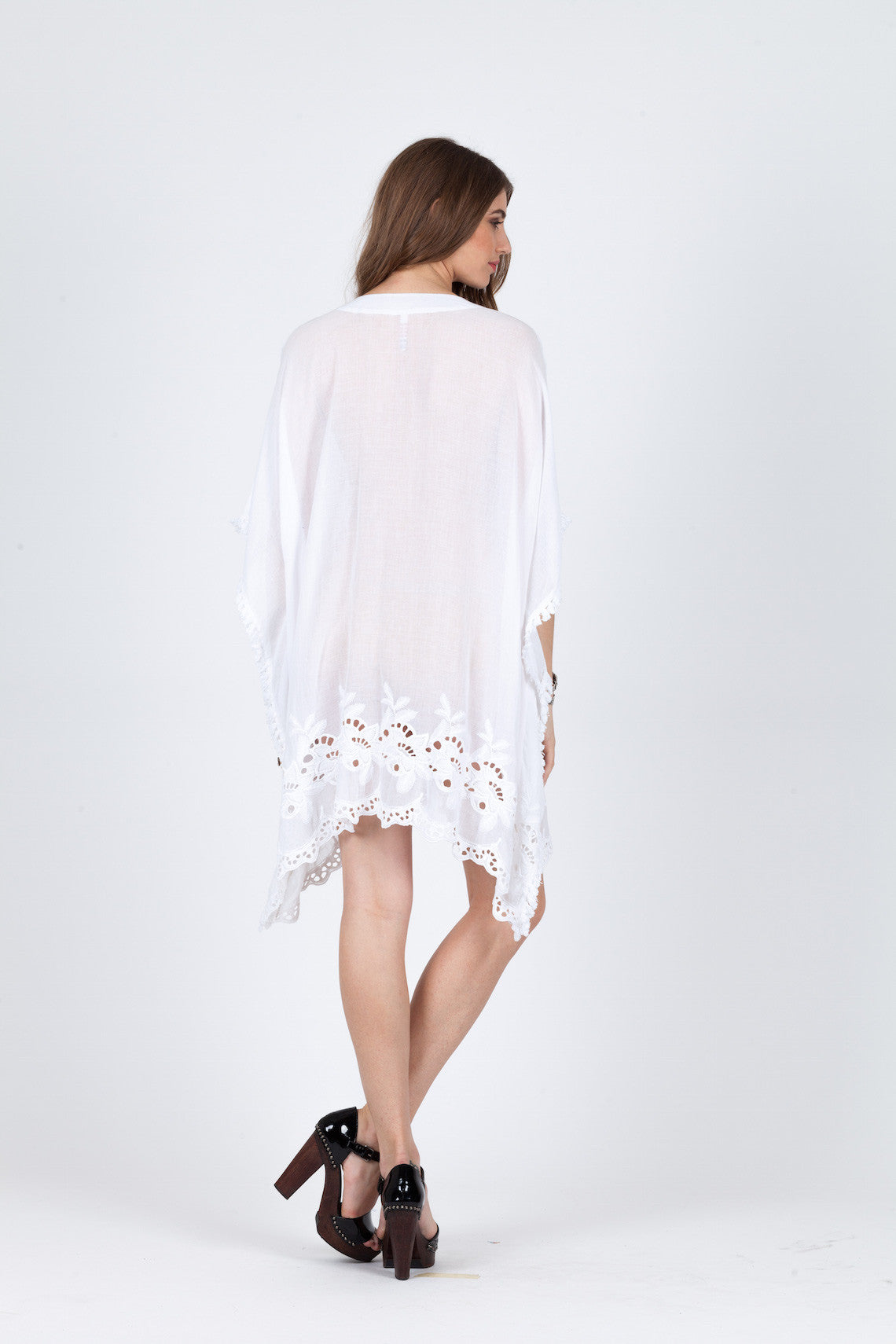 A woman poses against a plain background wearing the Native Warrior Tunic by RAGA, paired with black high-heeled sandals.