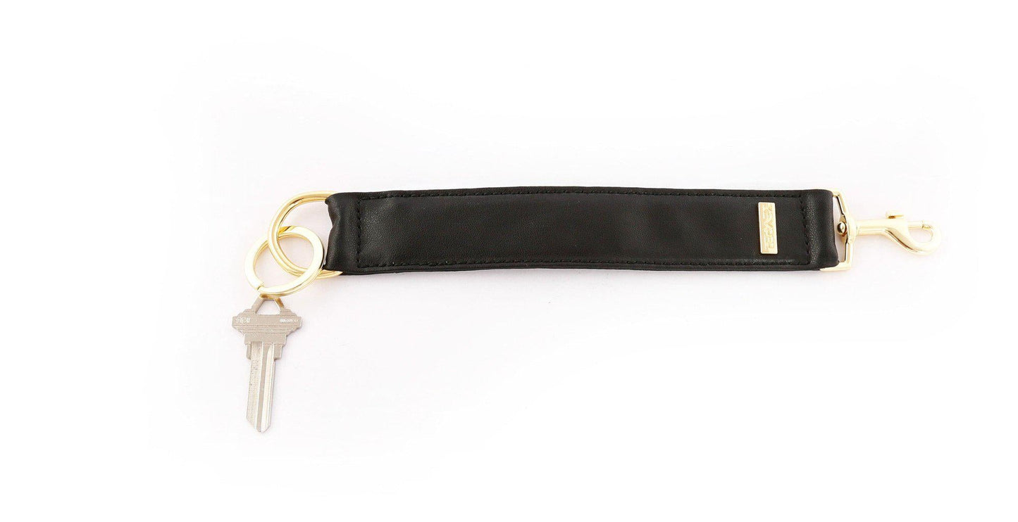 A Classic Black PREMIUM LEATHER KEYPER® key ring features a black leather bracelet with a gold clasp and branded KEYPER tag, attached to a key.