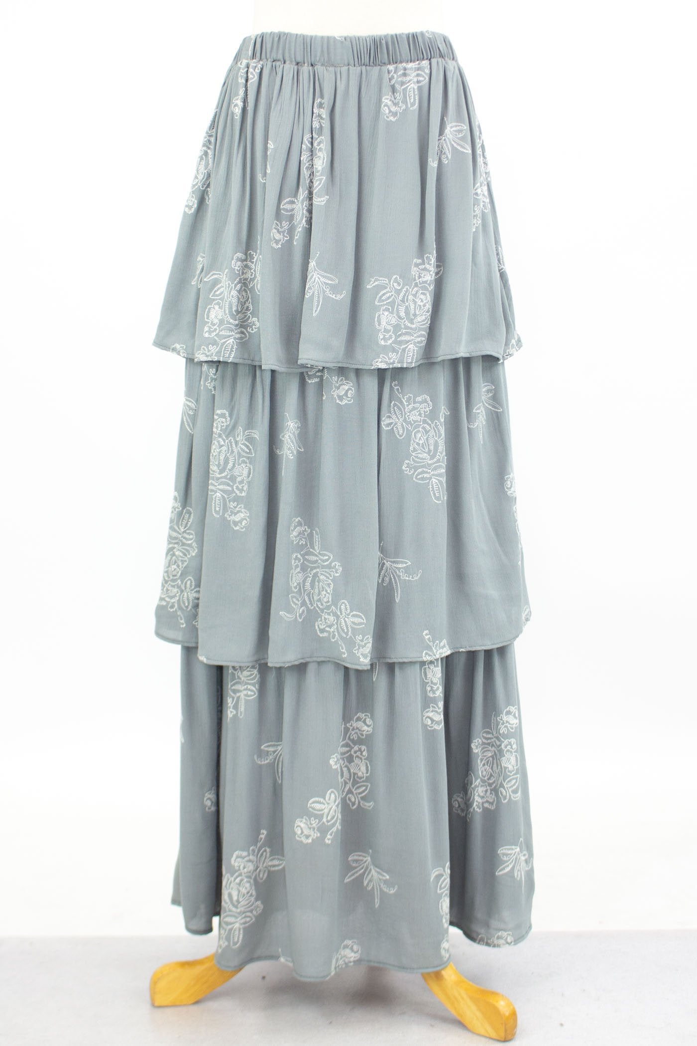 The mannequin displays the Stylespect Layered Ruffle Maxi Skirt in light gray, featuring white floral embroidery.