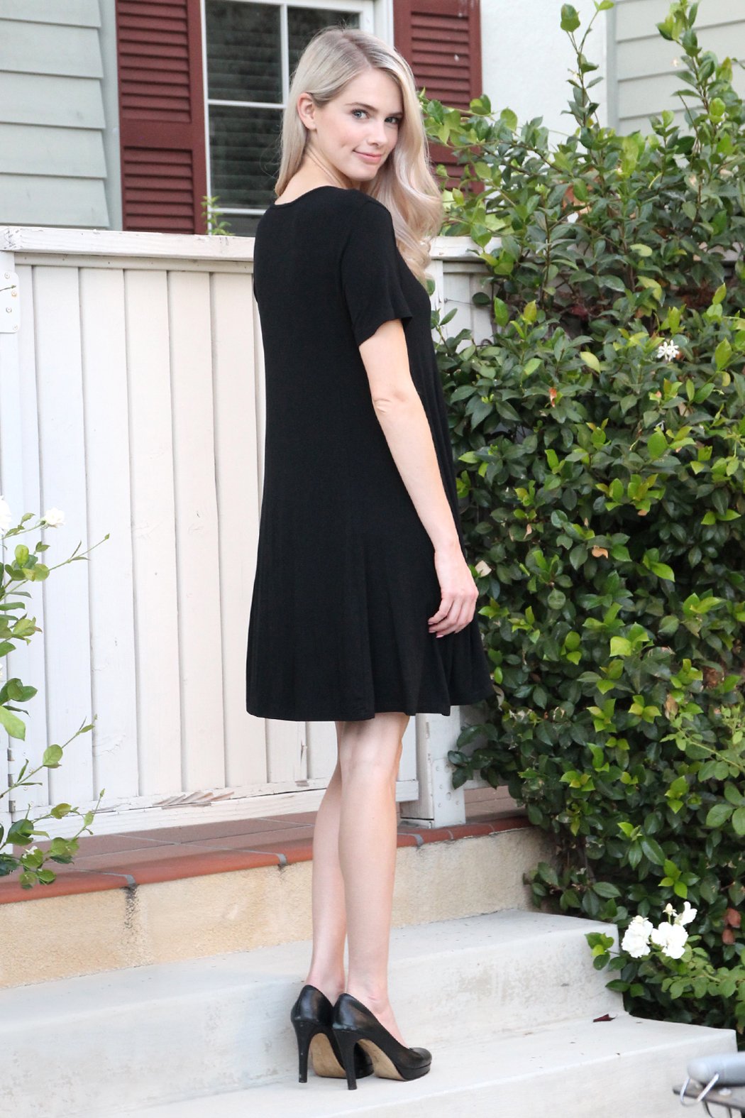 A person with long hair wearing a rust-colored Short Sleeve Strappy Pocket Dress by Riah Fashion stands on a staircase, holding the side of the dress with one hand.