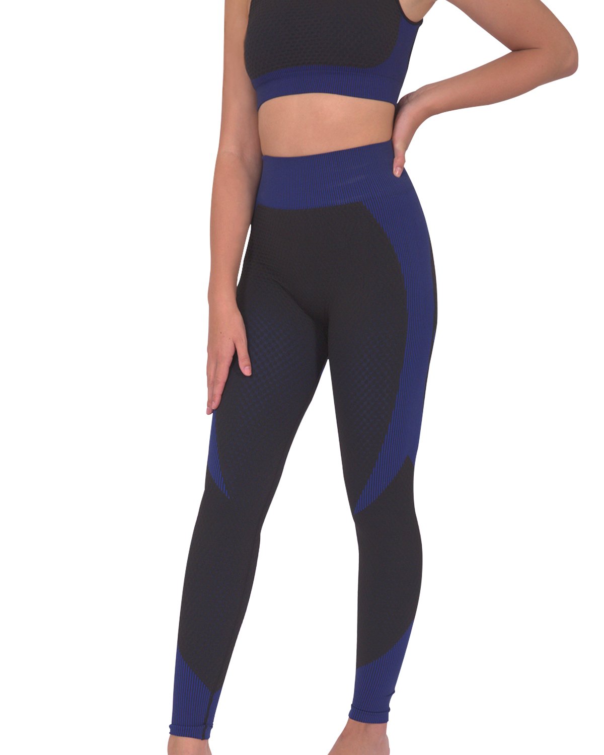 Someone wearing Savoy Actives Trois Seamless Legging in Black with Navy stands on a brown couch in a modern room with plants.