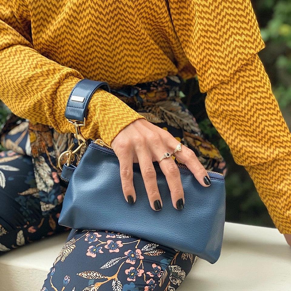 A compact True Navy vegan leather bag by KEYPER, with a gold zipper and clasp, comes with a detachable strap and includes a silver key attached to a key ring. Part of the 2-piece wristlet set.
