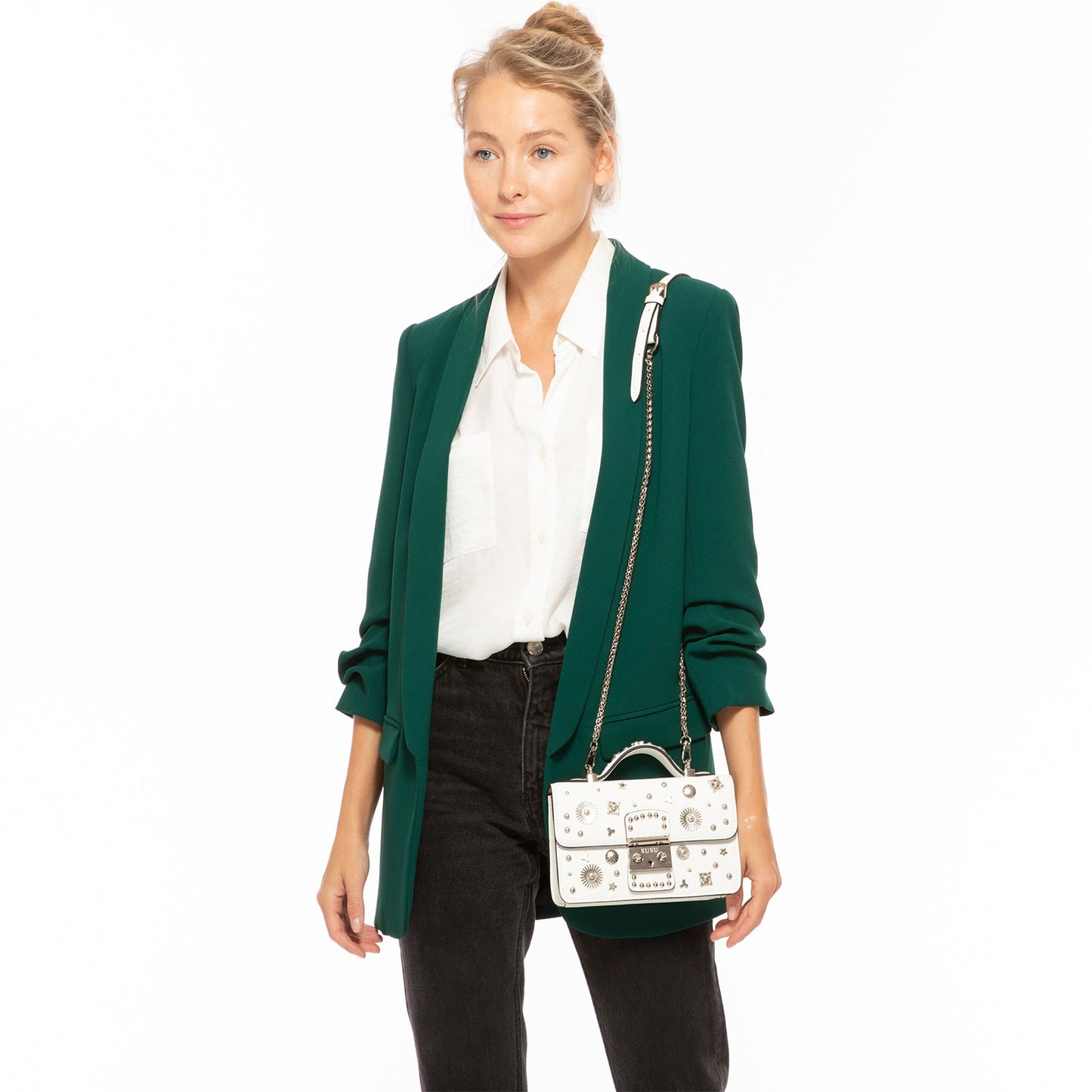 The Hollywood White Leather Crossbody Bag by SUSU features silver stud embellishments, a chain strap, a top handle, and a front clasp with the SUSU brand name.