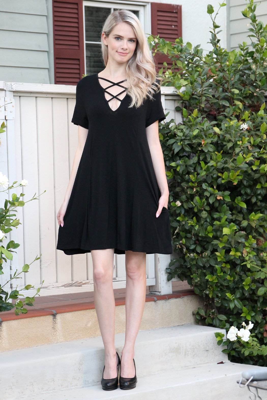 A person with long hair wearing a rust-colored Short Sleeve Strappy Pocket Dress by Riah Fashion stands on a staircase, holding the side of the dress with one hand.