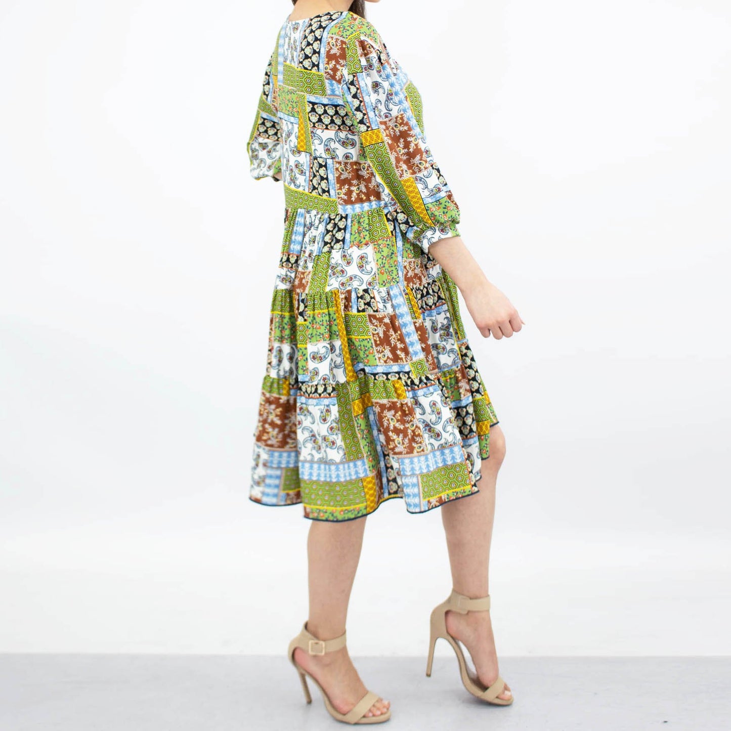 Person wearing a Stylespect Flare Bottom 3/4 Sleeve Dress in green, paired with beige heels, posing against a plain background.