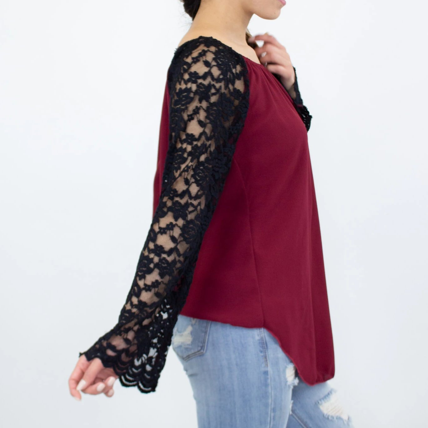 A person wearing a Stylespect Lace Sleeve Backless Top in burgundy and ripped jeans, standing against a plain white background.