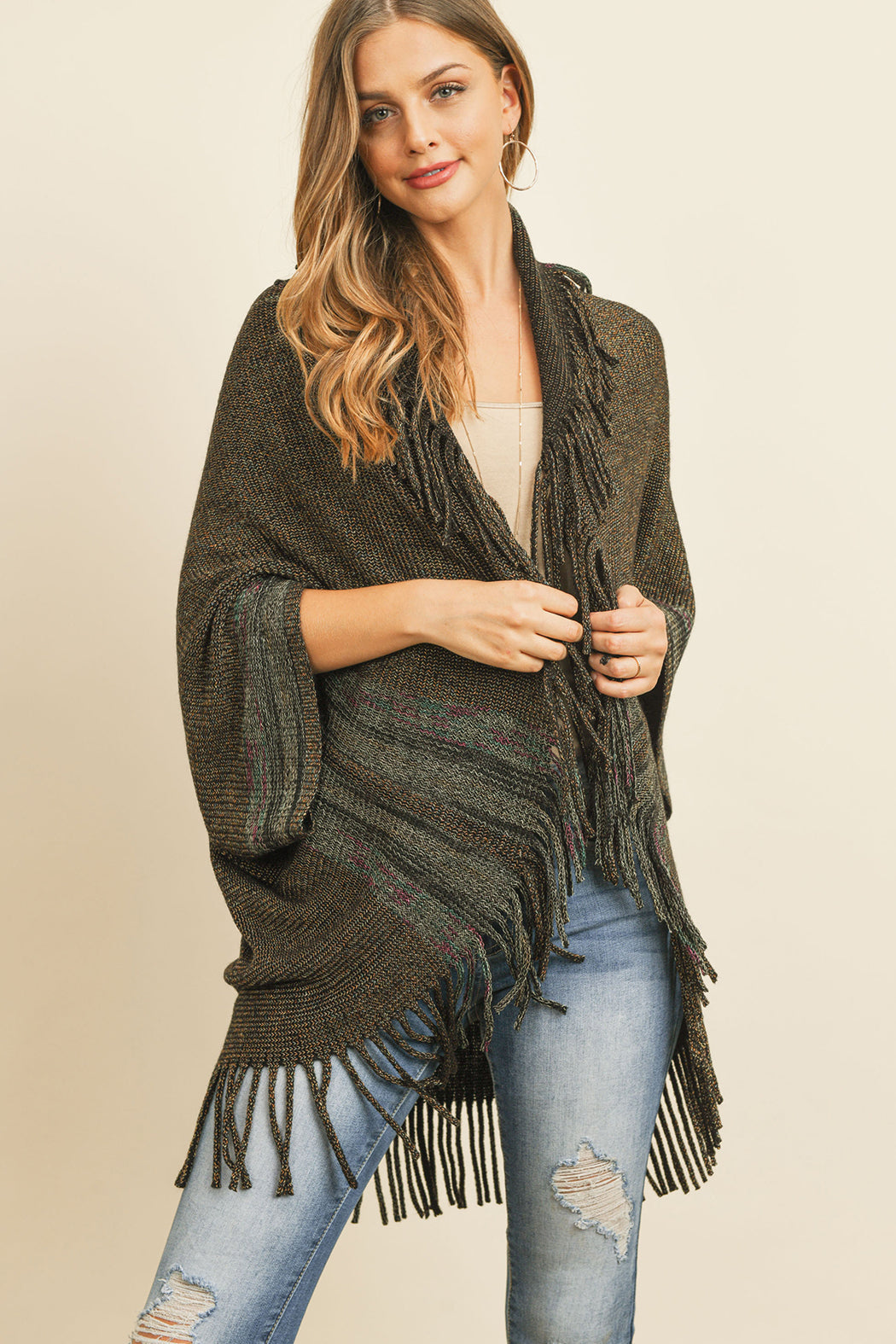 Someone is wearing a Fringe Stripe Open Front Kimono by Riah Fashion over a beige top and ripped jeans, standing against a plain background.