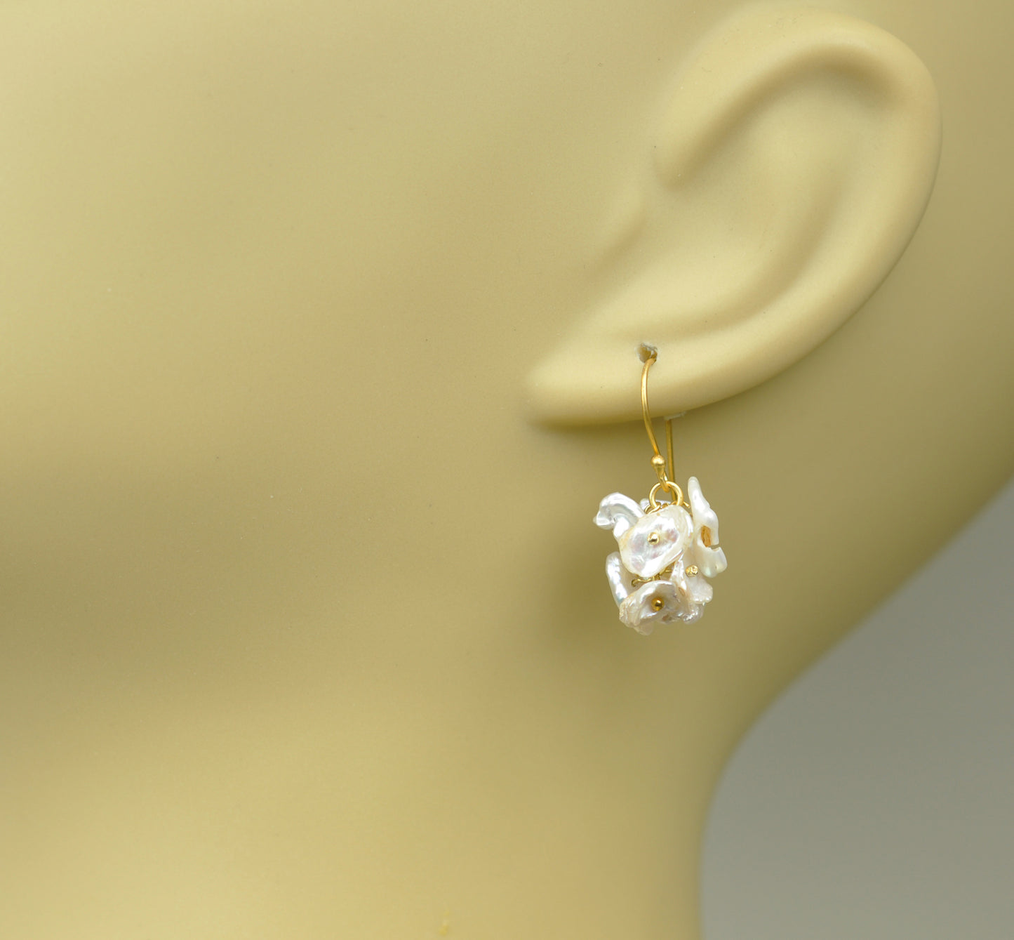 Gena Myints Short Keshi Pearl Cluster Earrings feature gold-hook dangling earrings adorned with clusters of petal-like motifs and gold bead accents.