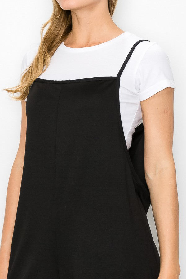 A person models the Stylespect Cropped Bottom Wide Leg Oversized Jumpsuit in black, paired with a white t-shirt and white sneakers, set against a plain white backdrop.