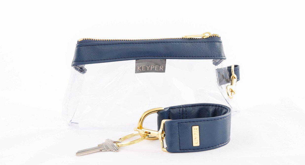 A compact True Navy vegan leather bag by KEYPER, with a gold zipper and clasp, comes with a detachable strap and includes a silver key attached to a key ring. Part of the 2-piece wristlet set.