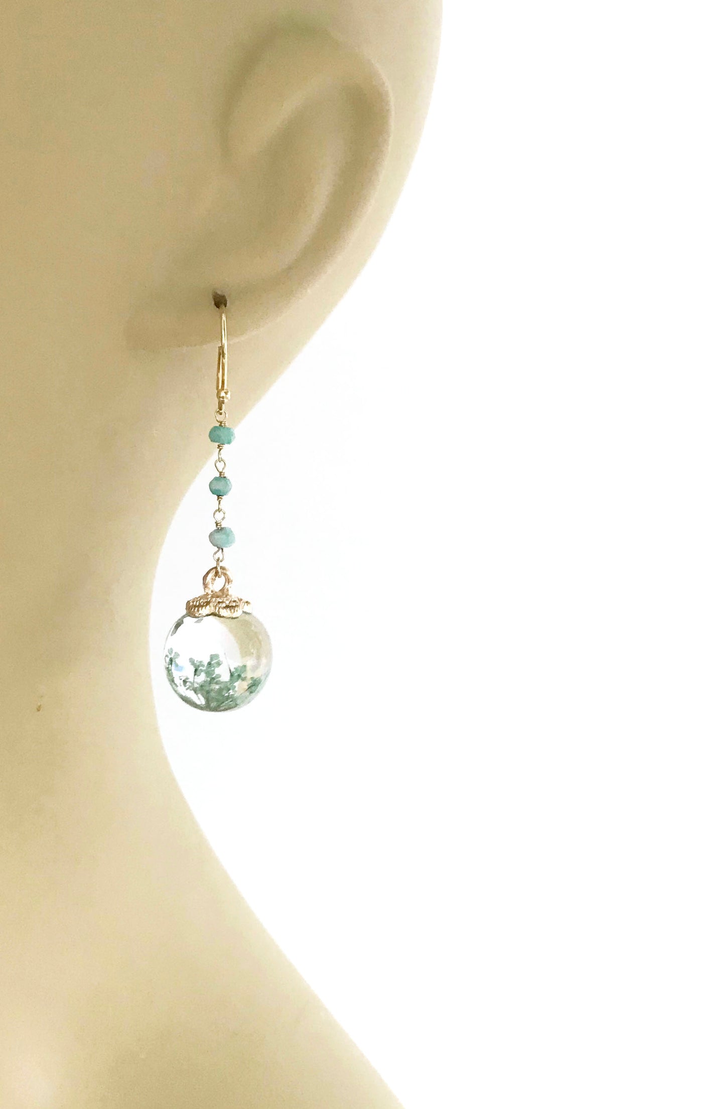 Gena Myints Petrified Flower Keepsake Amazonite Earrings feature dangling earrings with green beads and round spheres showcasing small plant-like designs.