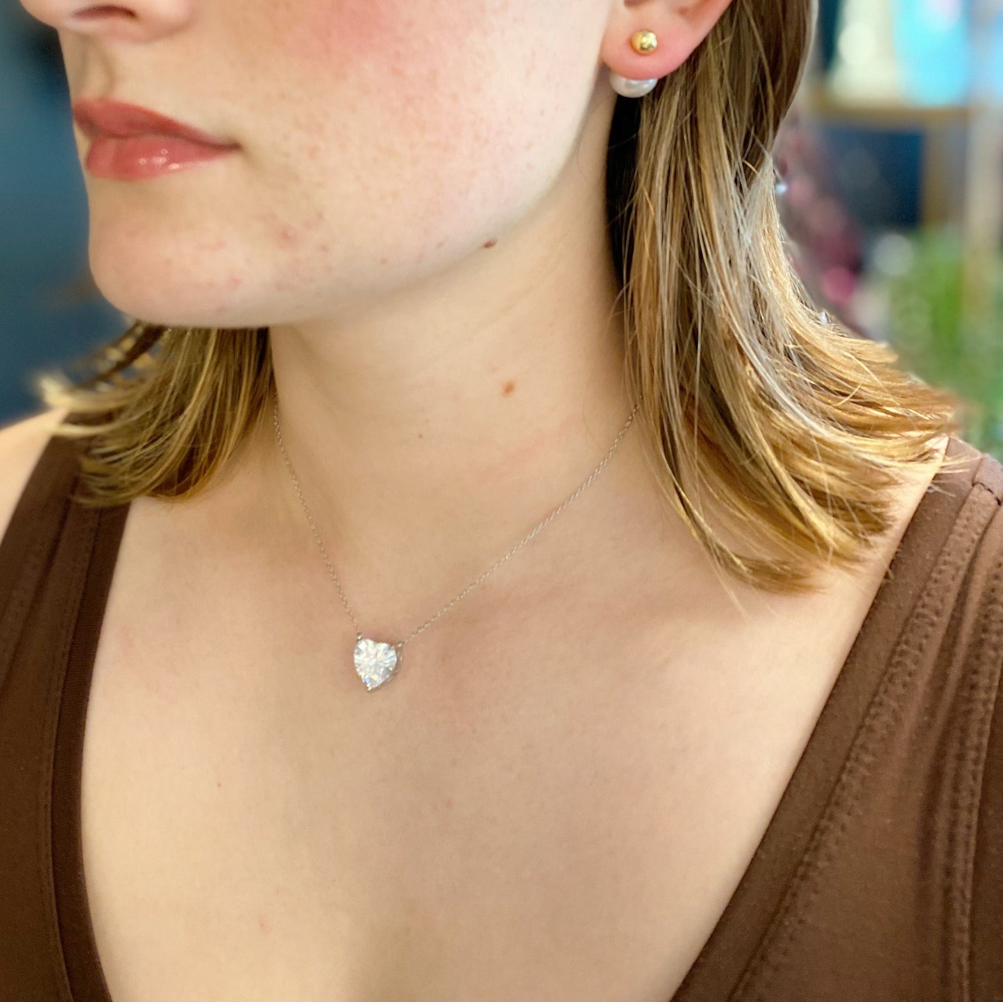 Two Absolute Beauty sterling silver heart necklaces by Ellison + Young; one with a pink gem, the other with a clear gem, against a white background.