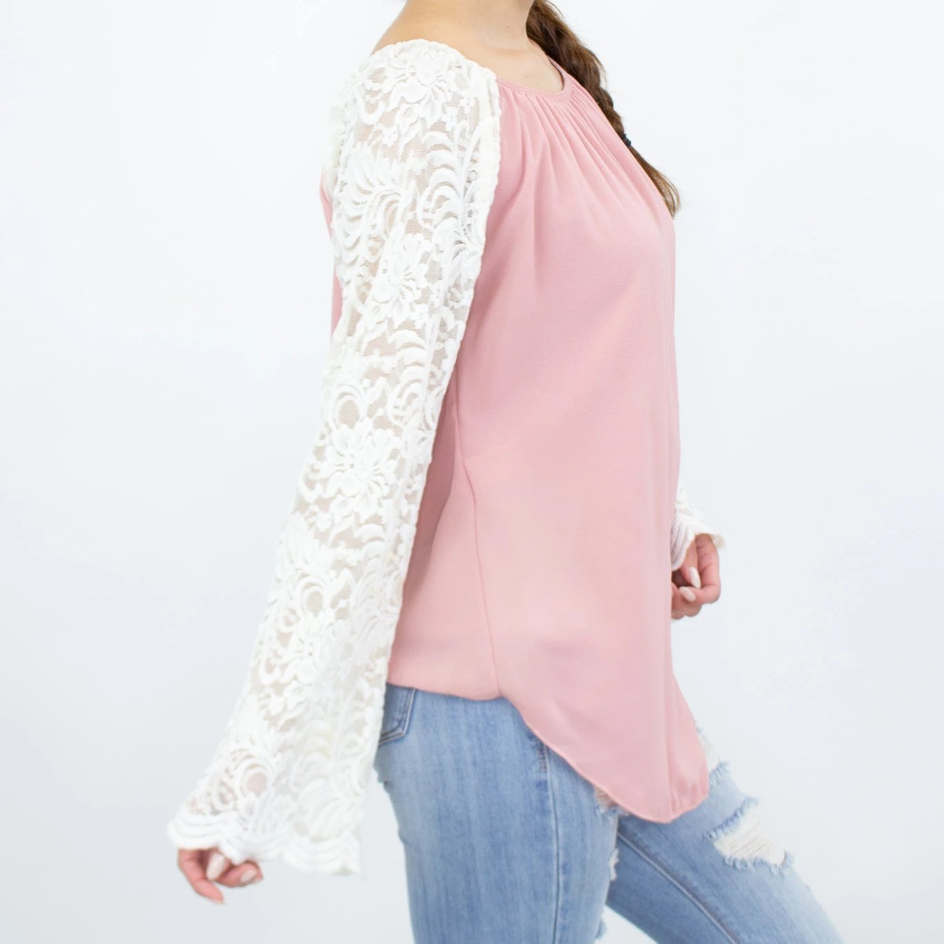 A person in a Stylespect Lace Sleeve Backless Top - Rose with ripped jeans stands against a plain background.
