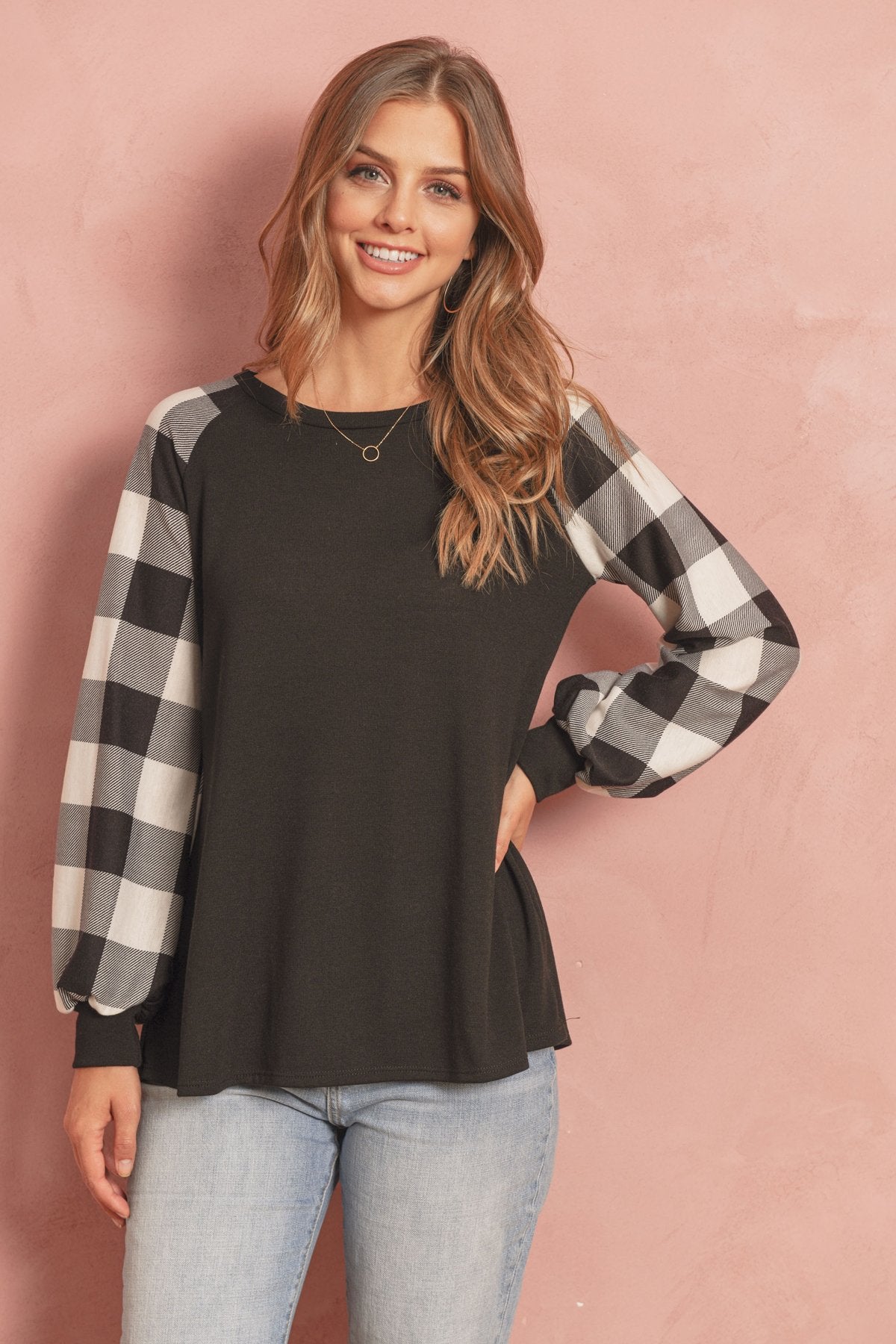 A woman wearing a faded denim plaid puff sleeved round neck top by Riah Fashion and ripped jeans stands against a plain background.