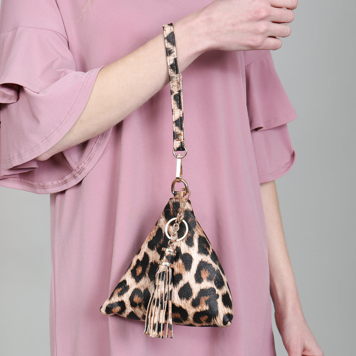 A person in a white shirt and jeans is holding the Riah Fashion Pyramid Shape Tassel Wristlet Leather Bag in orange.