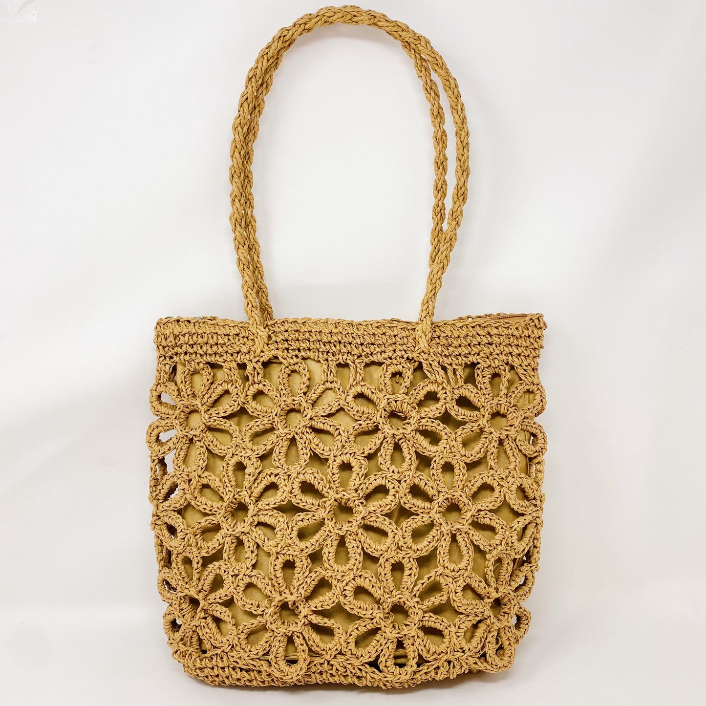 A person smiles while standing outdoors with a clear blue sky and trees in the background, wearing a yellow striped sweater and holding an Ellison + Young Hand Made Muted Floral Tote.