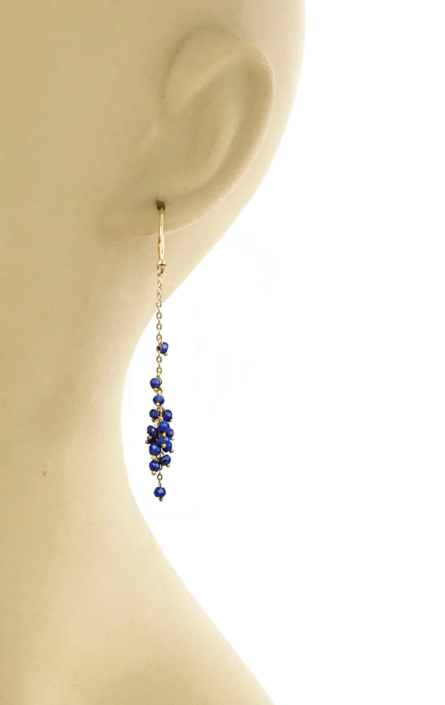 Gena Myints Cascading Lapis Lazuli Cluster Earrings feature gold hooks with dangling clusters of small blue beads.