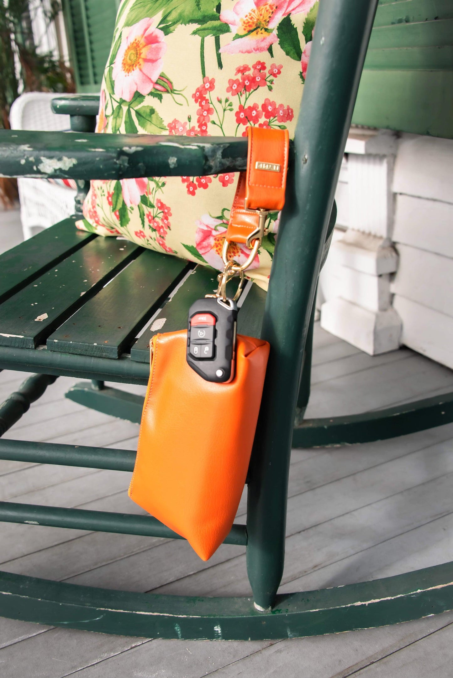 The KEYPER Persimmon Vegan Leather 2-Piece Wristlet Set features a clutch bag with a gold zipper, detachable strap, and small gold keychain.