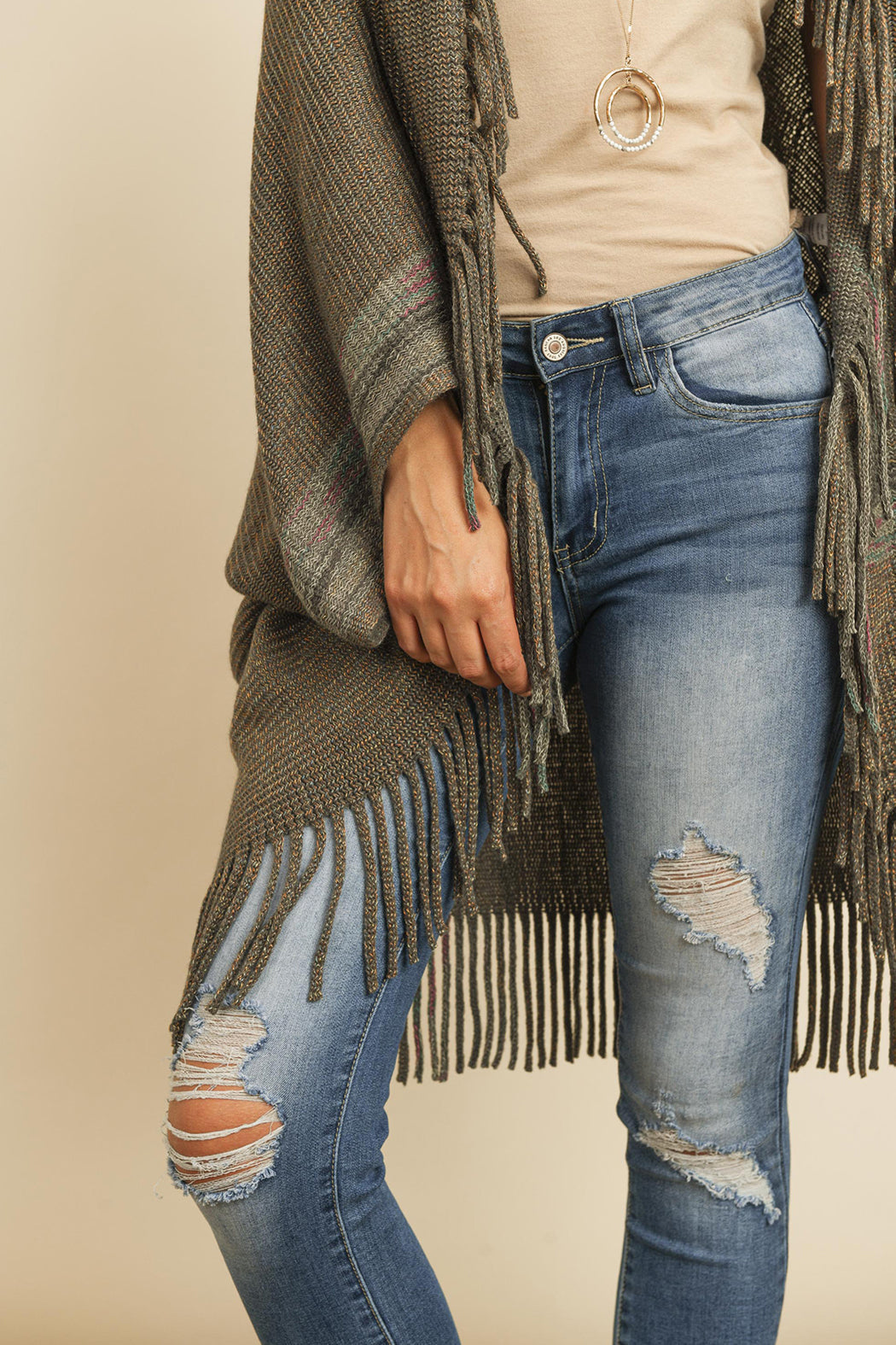 Someone is wearing a Fringe Stripe Open Front Kimono by Riah Fashion over a beige top and ripped jeans, standing against a plain background.