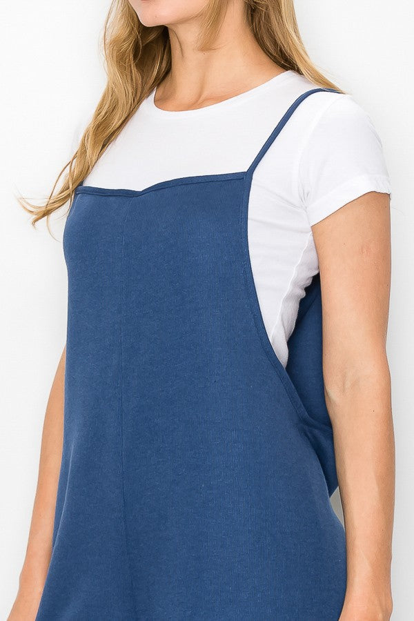 A person wearing a Stylespect Cropped Bottom Wide Leg Oversized Jumpsuit in blue over a white T-shirt and white sneakers, standing and smiling against a plain white background.