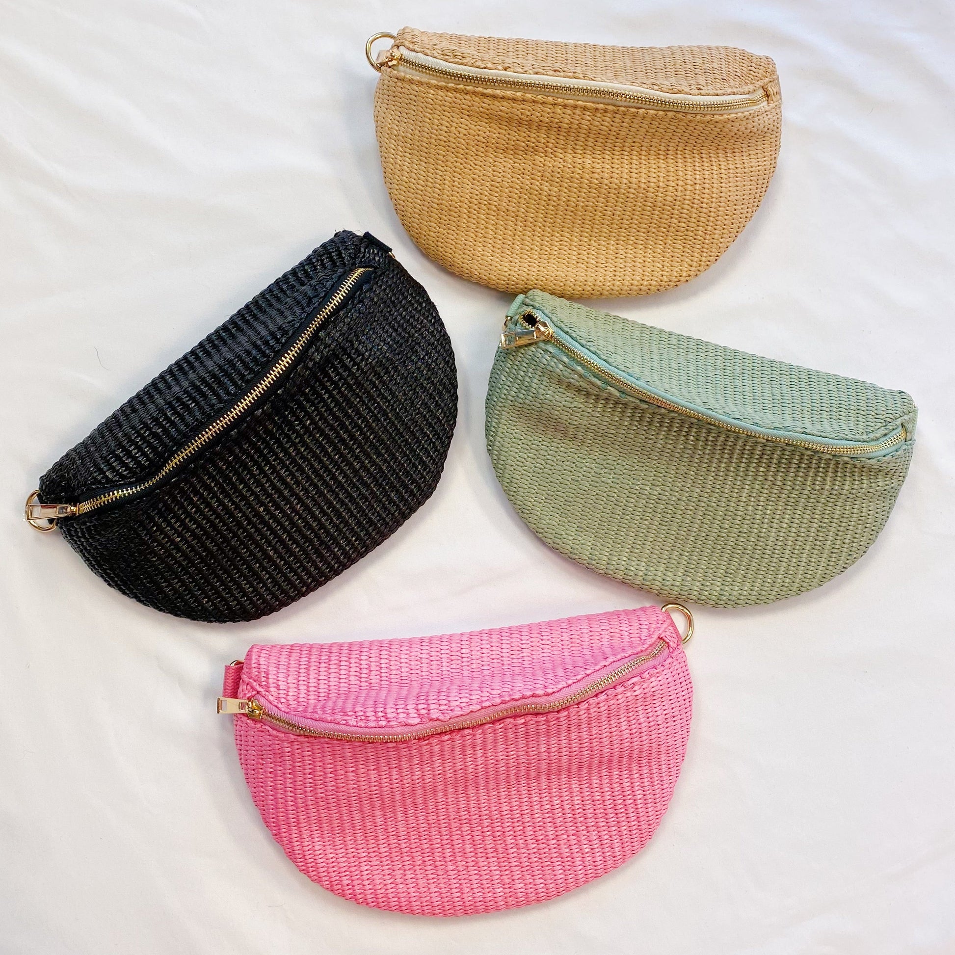 Four Bahama Breeze Fit All Sling Bags by Ellison + Young in pink, black, beige, and green with unique patterned straps are displayed on a white surface.