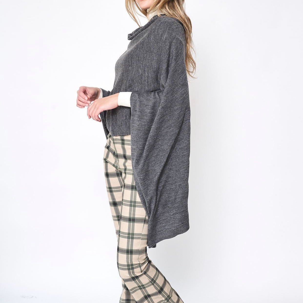 Someone wearing the Take With Me Travel Poncho by Ellison + Young with plaid pants against a plain white background.