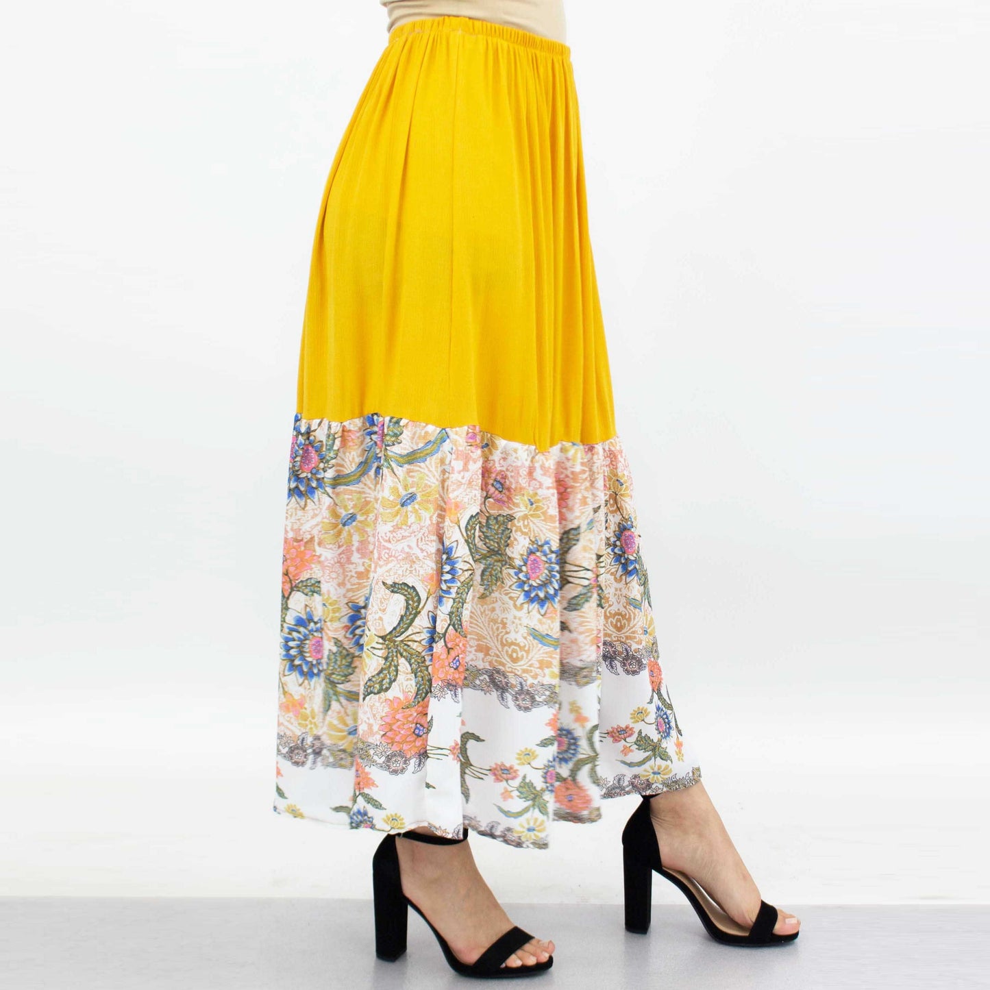 A person wearing a Stylespect Floral Color Block Skirt - Yellow paired with black high heels.