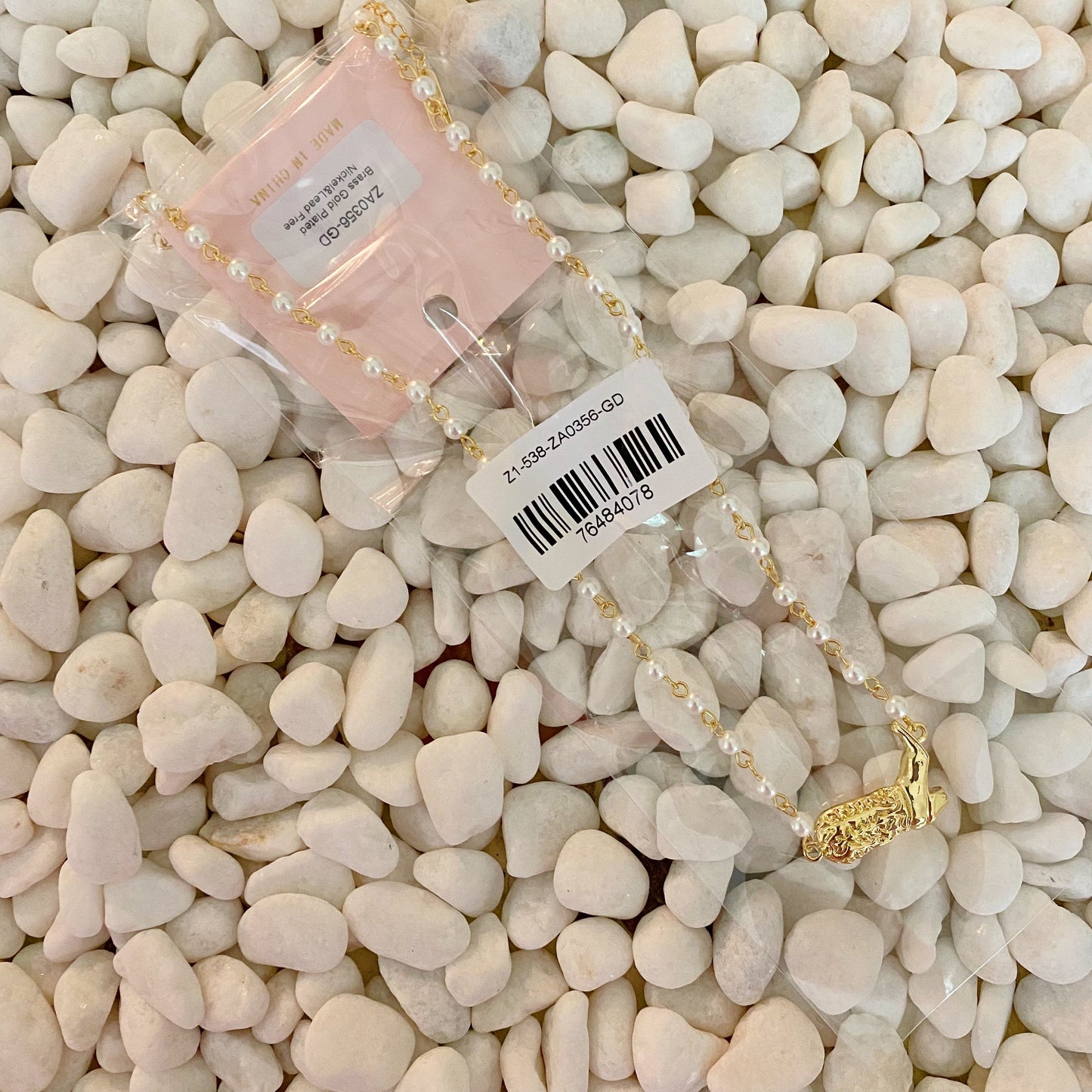 Ellison + Youngs Cowgirl Boot Pearl Chain Necklace is displayed on a marble surface.