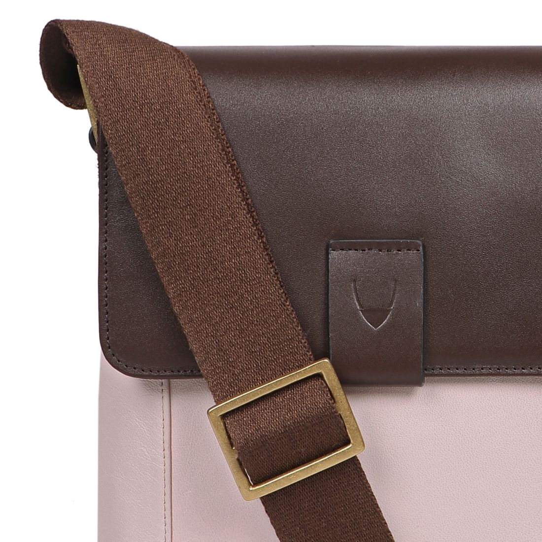 The Aiden Genuine Leather Mini Crossbody by Hidesign is a brown leather shoulder bag featuring a flap cover and an adjustable fabric strap with a brass buckle.